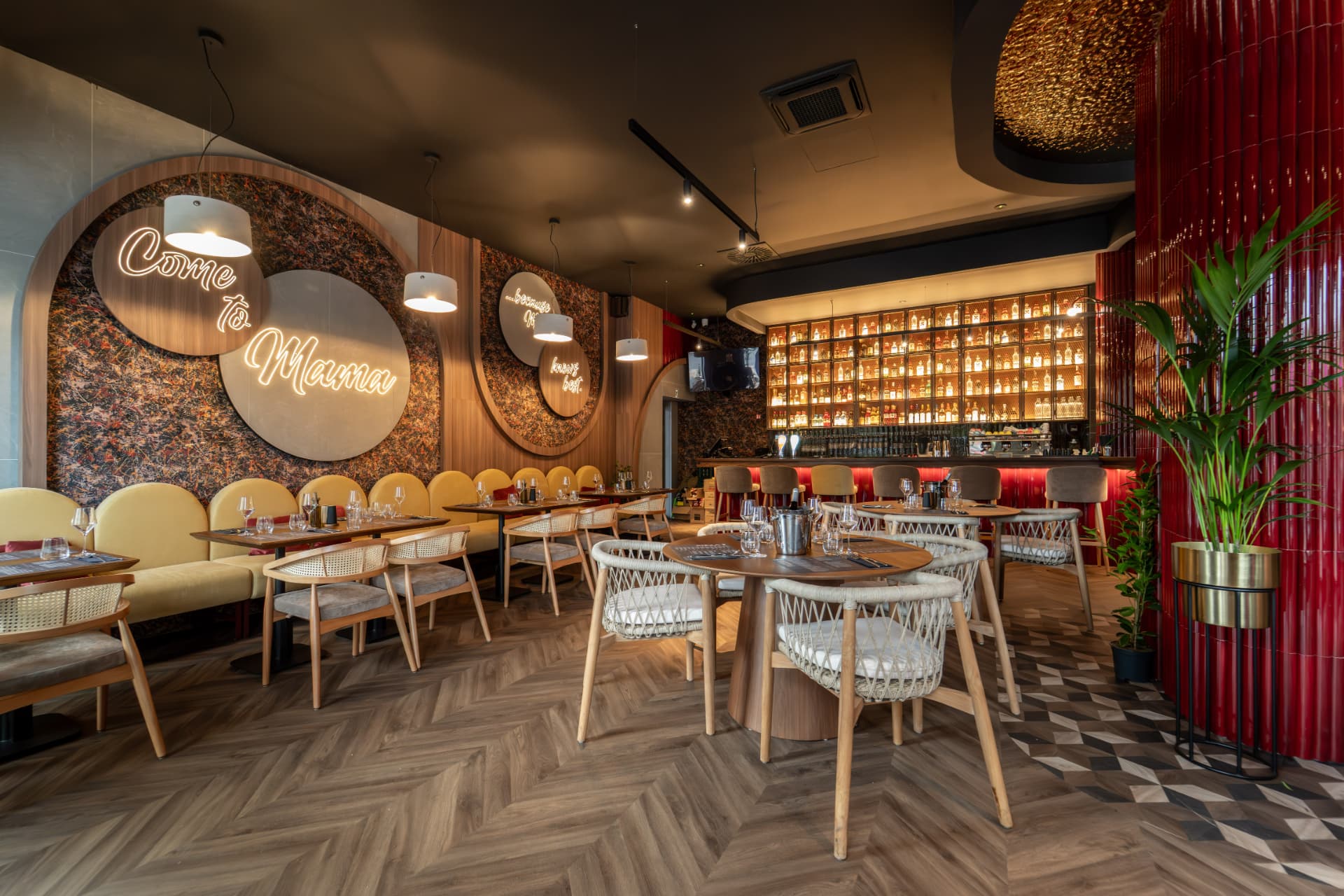Interijer restorana s neonskim natpisom, žutim sjedalima i osvijetljenim barom