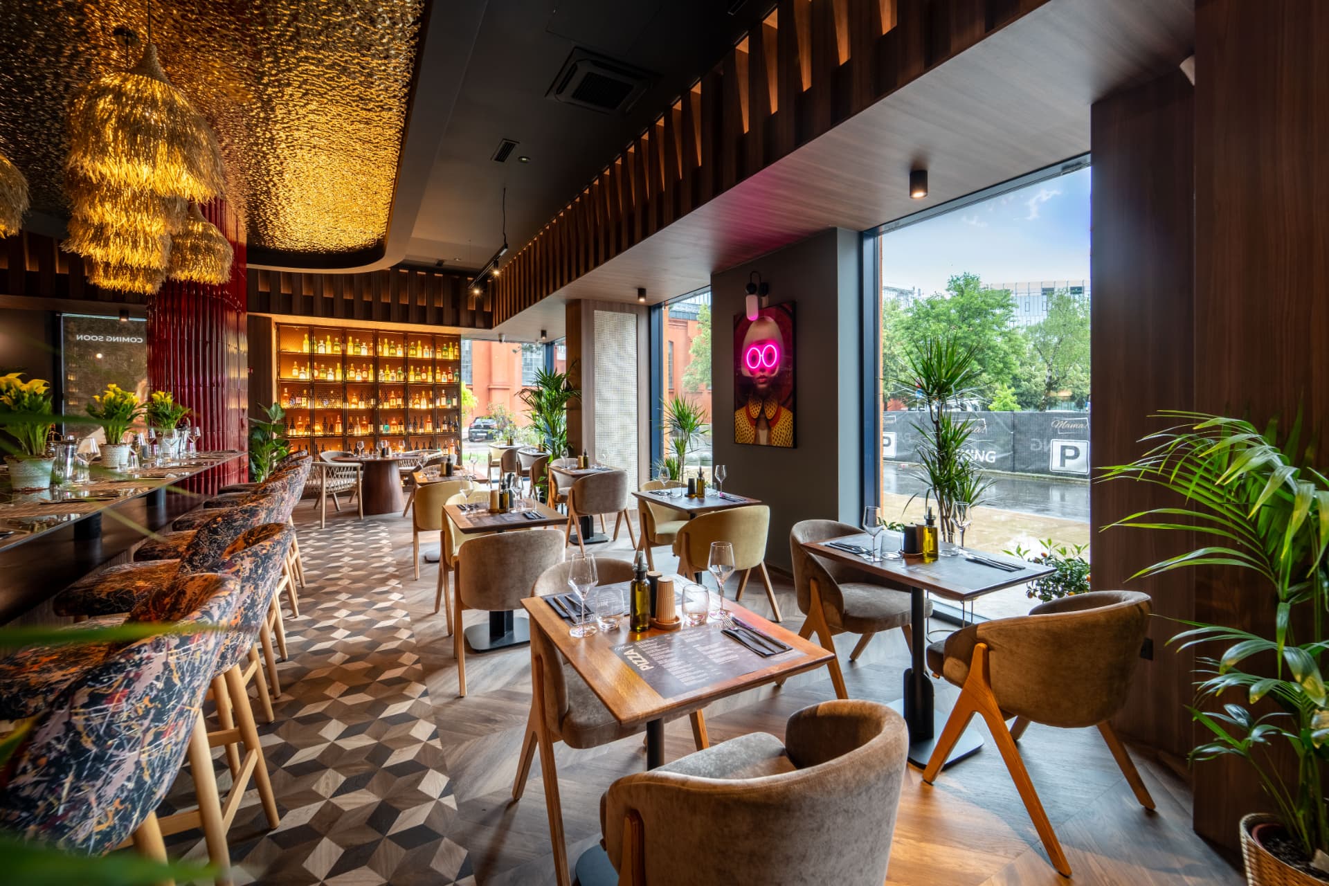 Restoran s pogledom na velike prozore, zlatnim stropom i drvenim stolovima